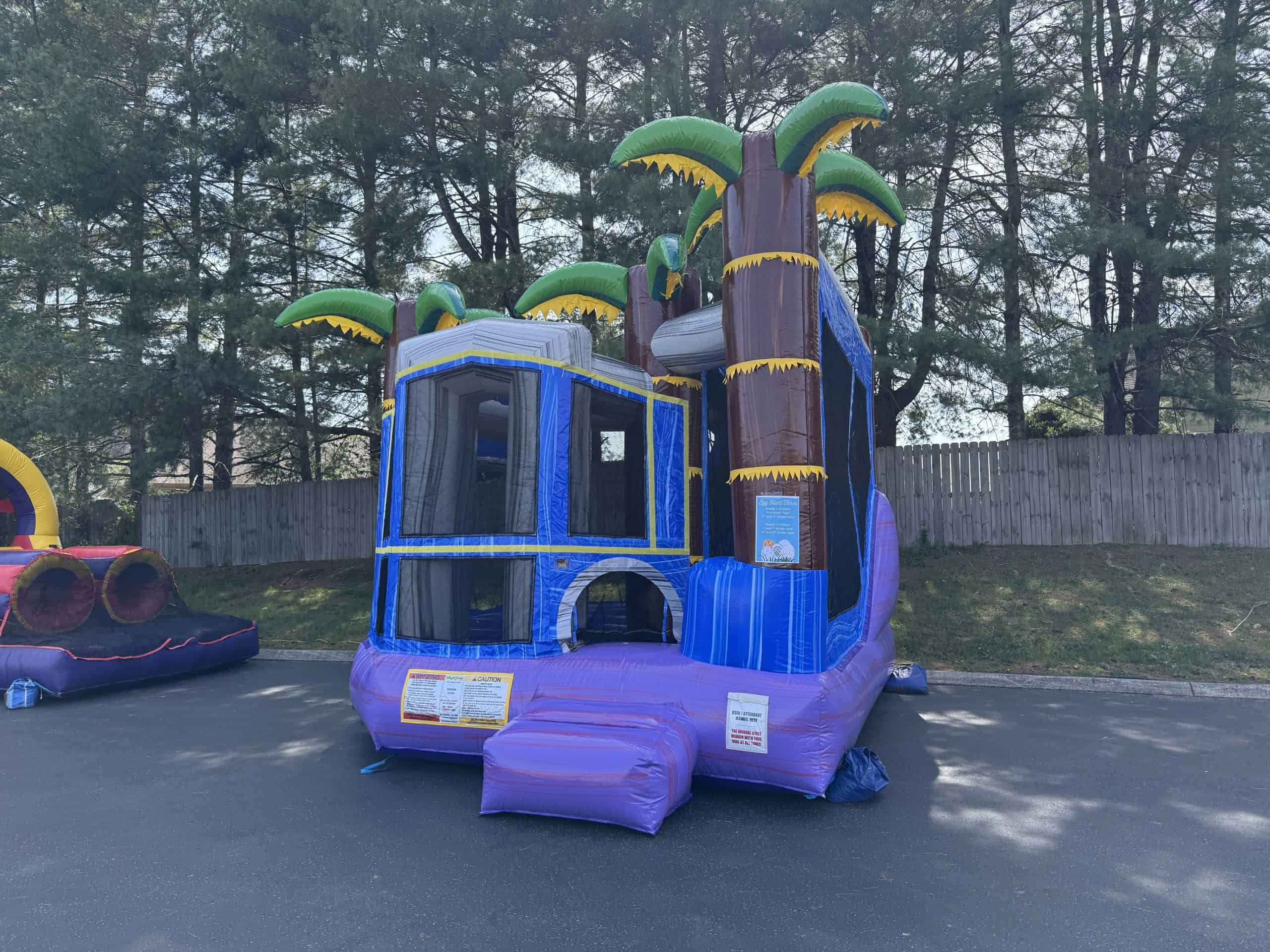 Inflatable jungle-themed bounce house with palm trees for kids' parties.